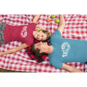 young couple laying on a picnic blanket wearing red and aqua vegan shirts saying eat more plants in the shape of an avocado from ethical clothing brands