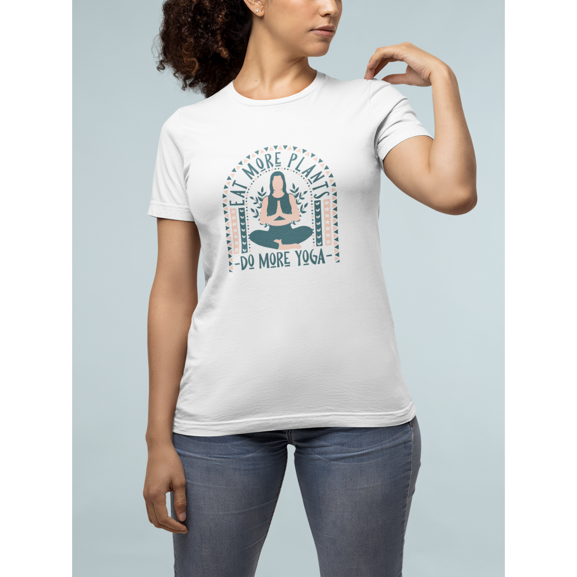 woman standing touching shoulder with "eat more plants, do more yoga" boho style design in dark grey and light muted pink, on a white premium tee, vegan workout clothes from ethical clothing brands