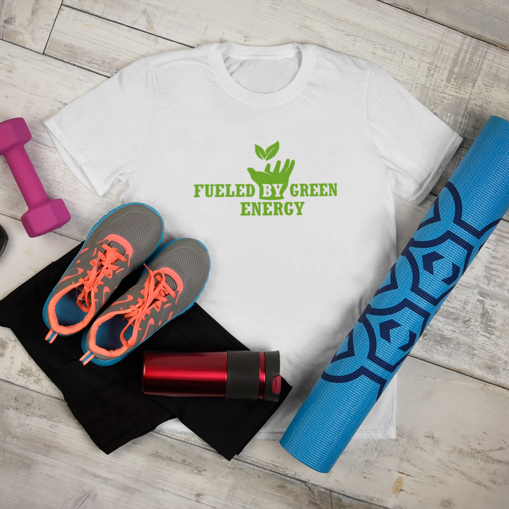 Vegan workout clothes on a white-washed wooden floor featuring a vegan t shirt with vibrant green design saying "fueled by green energy" with a hand holding up an elevated leaf, on a white premium tee