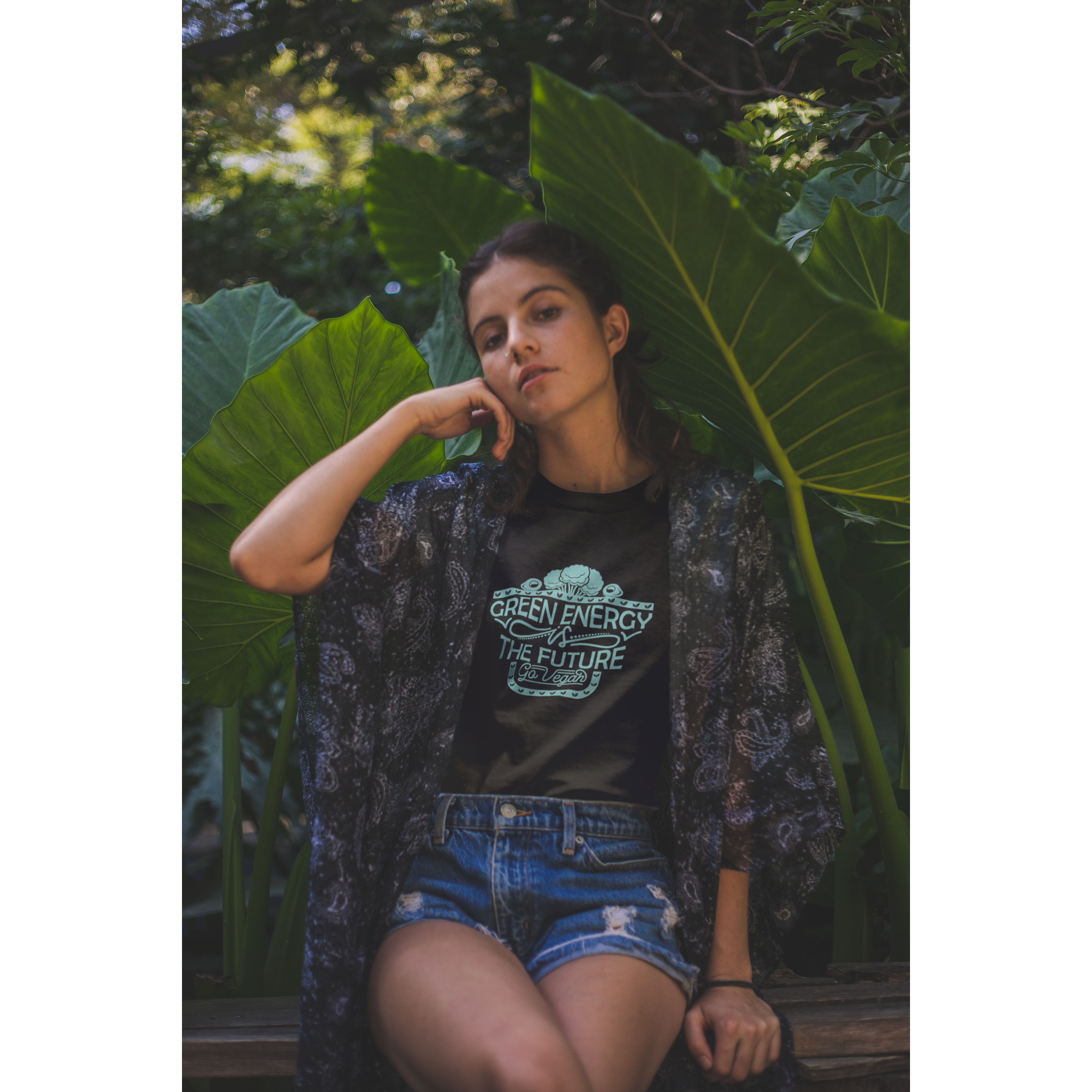 woman in front of plants wearing black vegan shirt saying "green energy is the future, go vegan", from ethical clothing brands and companies that donate to nonprofits