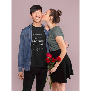 man wearing "I met her in the produce section" design for vegan couples with white words and a grey arrow through a heart-shaped peach on a black vegan shirt, from ethical clothing brands and companies that donate to nonprofits