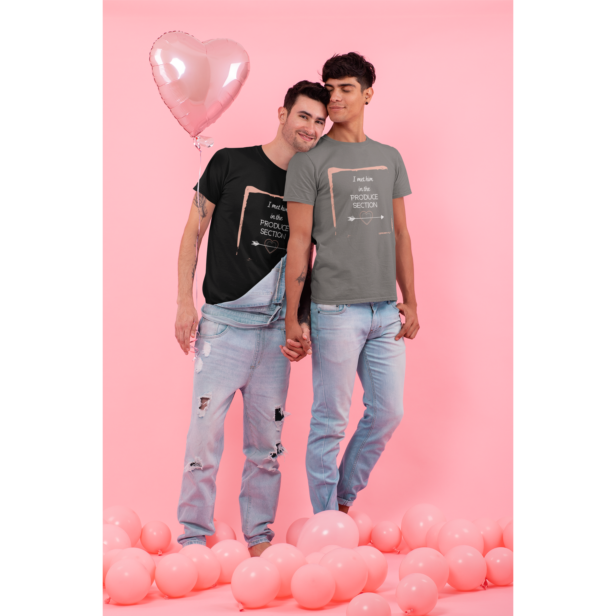 two men standing with pink balloons, male vegan couple wearing black and asphalt colored vegan t-shirts with I met him in the produce section words with an arrow through a heart and a pink painted frame 