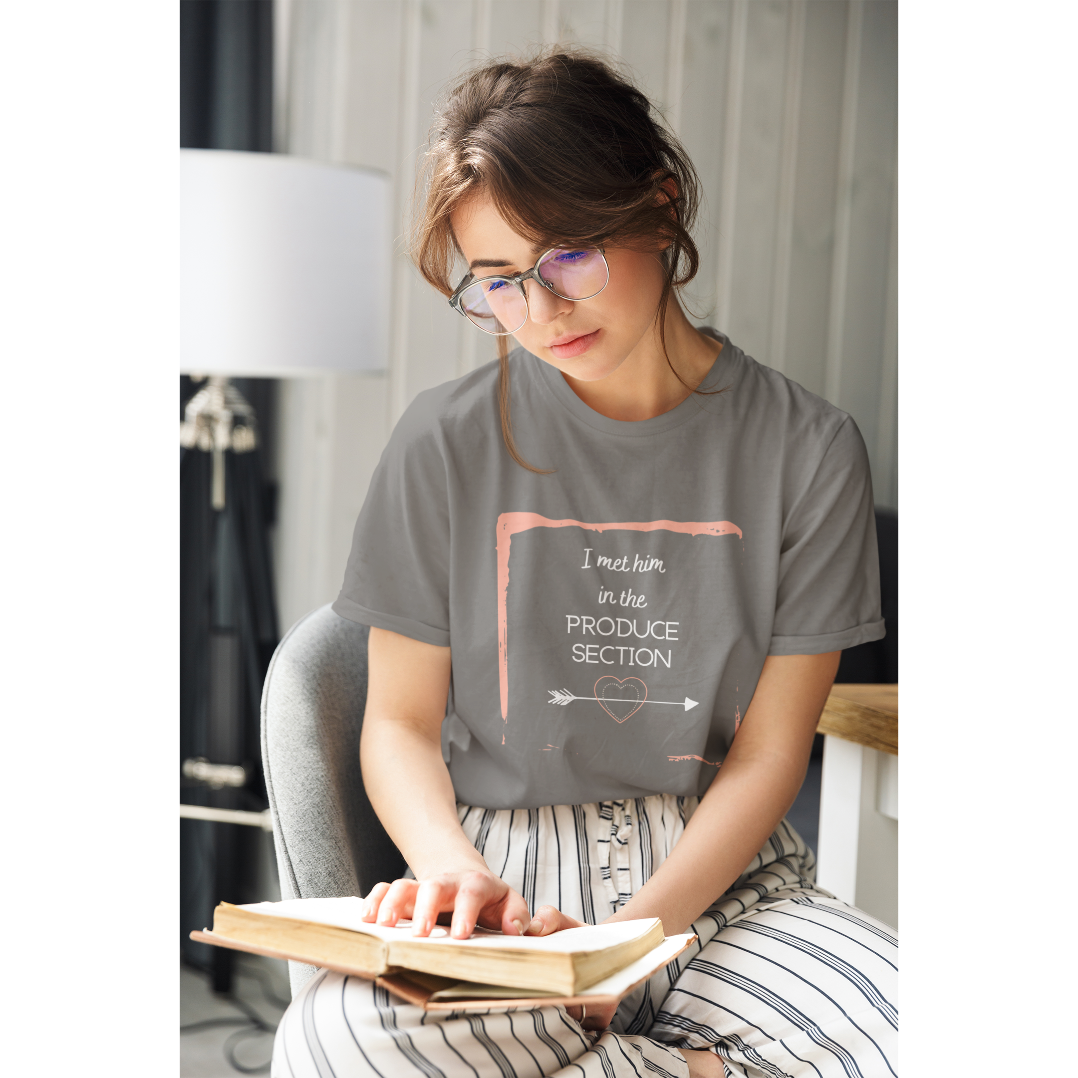 woman reading while wearing I met him in the produce section design for vegan couples with white words and a arrow through a heart, with a pink frame, on an asphalt colored vegan t shirt, from ethical clothing brands and companies that donate to nonprofits