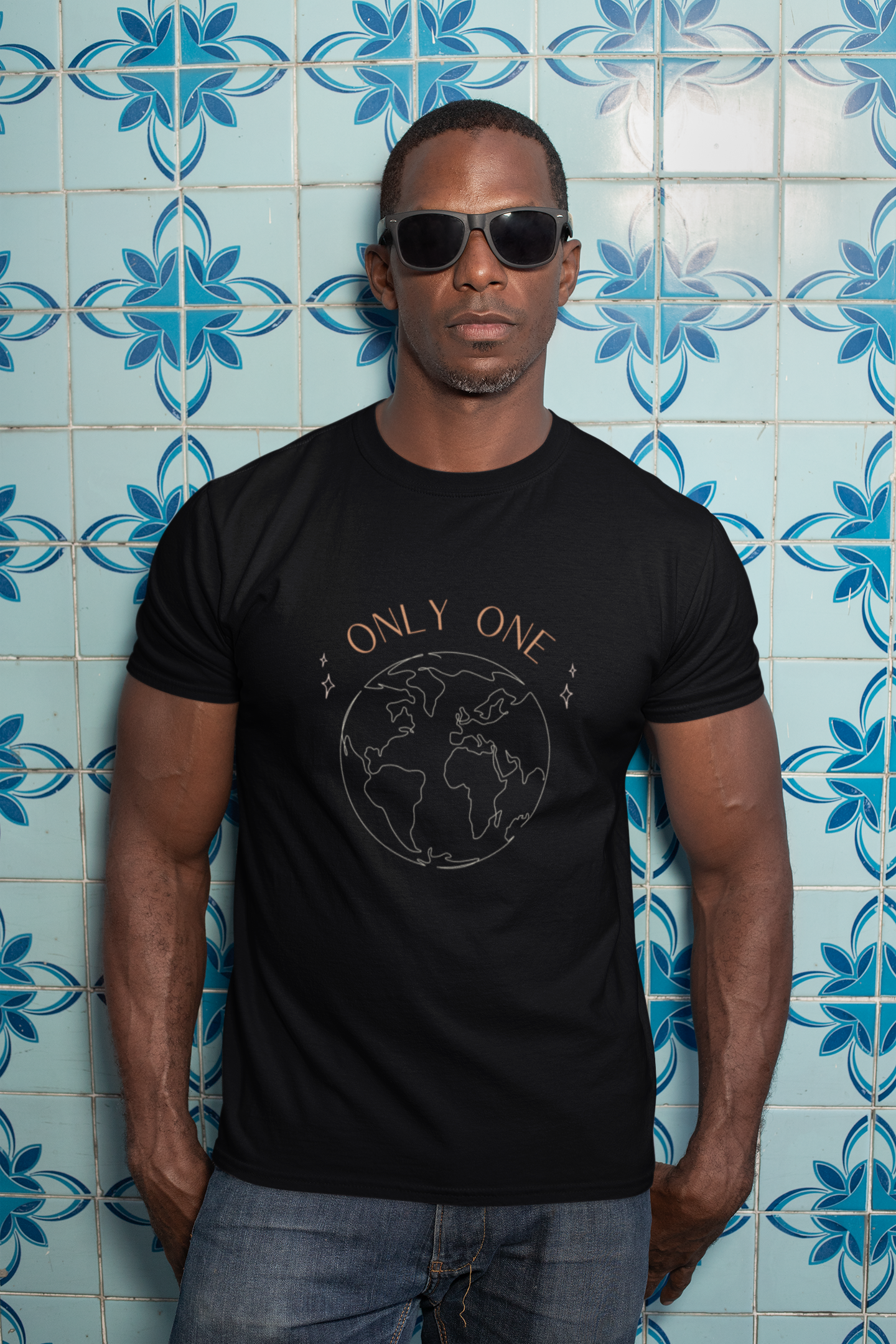 man with sunglasses against a vibrant tile wall wearing an organic vegan t-shirt saying only one earth