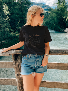 smiling woman outdoors wearing an organic vegan t-shirt in black color saying Only one earth