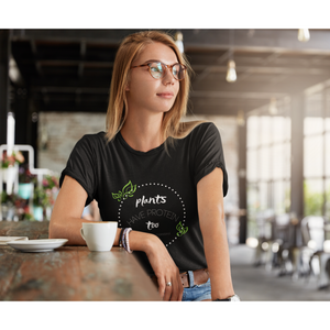 vegan shirts design worn by young woman in coffee shop,  white lettering and green leaves on a black premium tee that says plants have protein too without the cholesterol