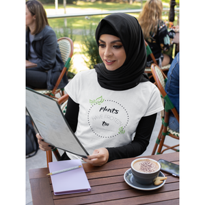 woman wearing hijab and a vegan t shirt at an outdoor cafe,  black lettering and green leaves on a white premium cotton tee that says plants have protein too without the cholesterol