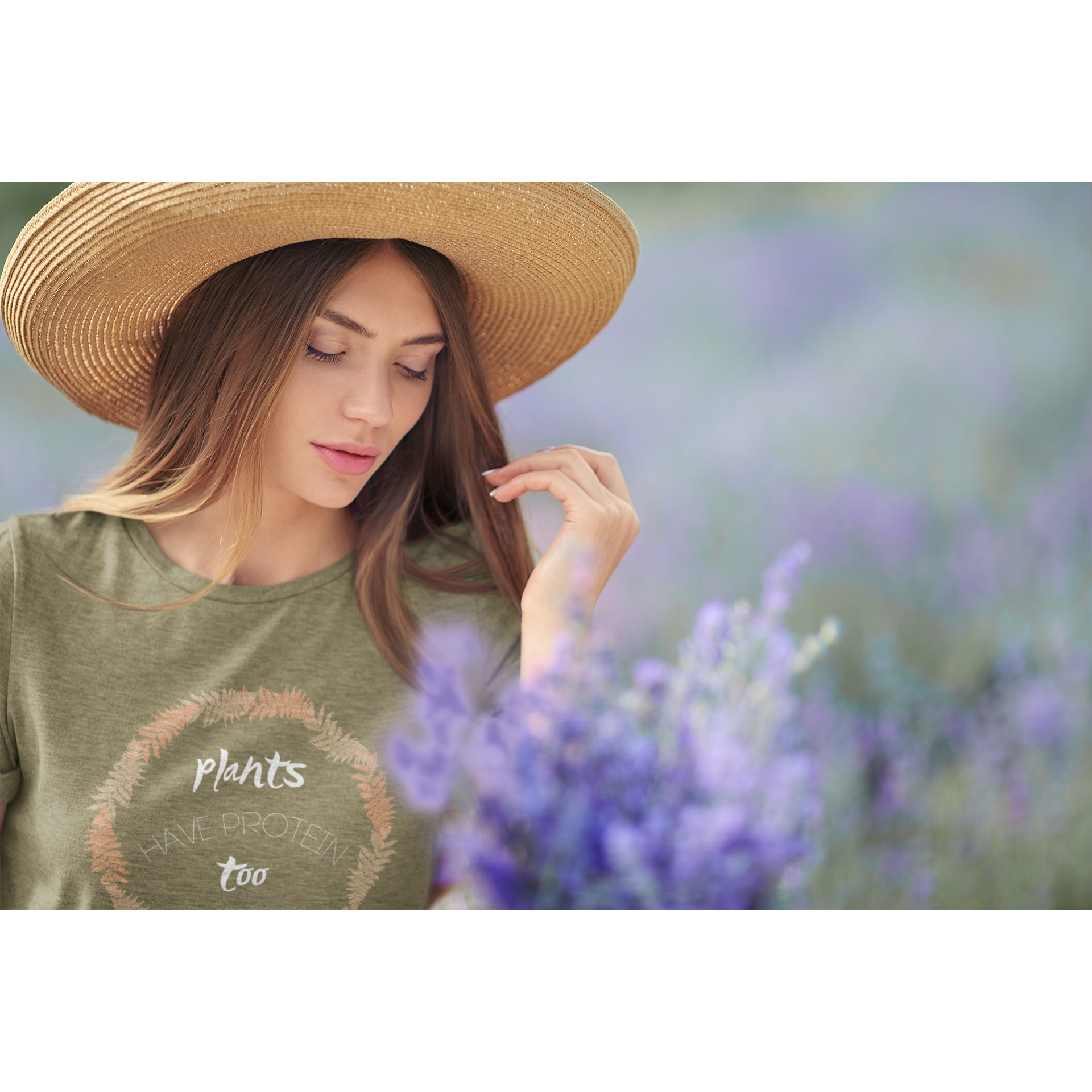 woman in a lavender field wearing a heather olive vegan t shirt with white lettering and tan and peach fern circle, saying plants have protein too without the cholesterol