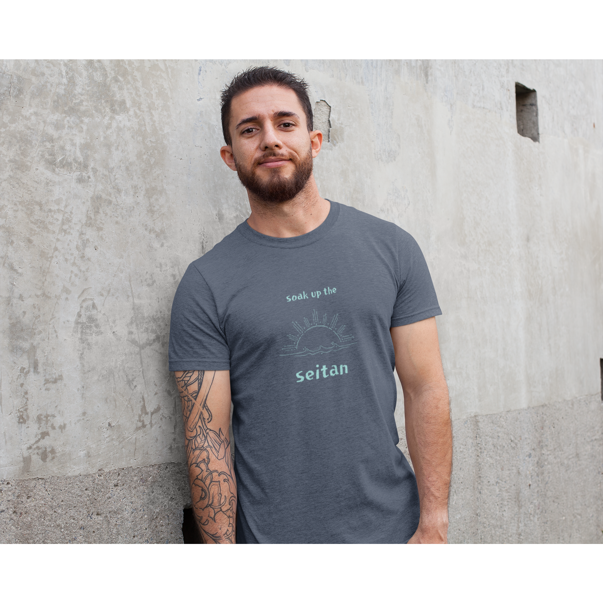 vegan t shirts design using heather navy fabric with a teal design saying soak up the seitan worn by a man smiling in the sun