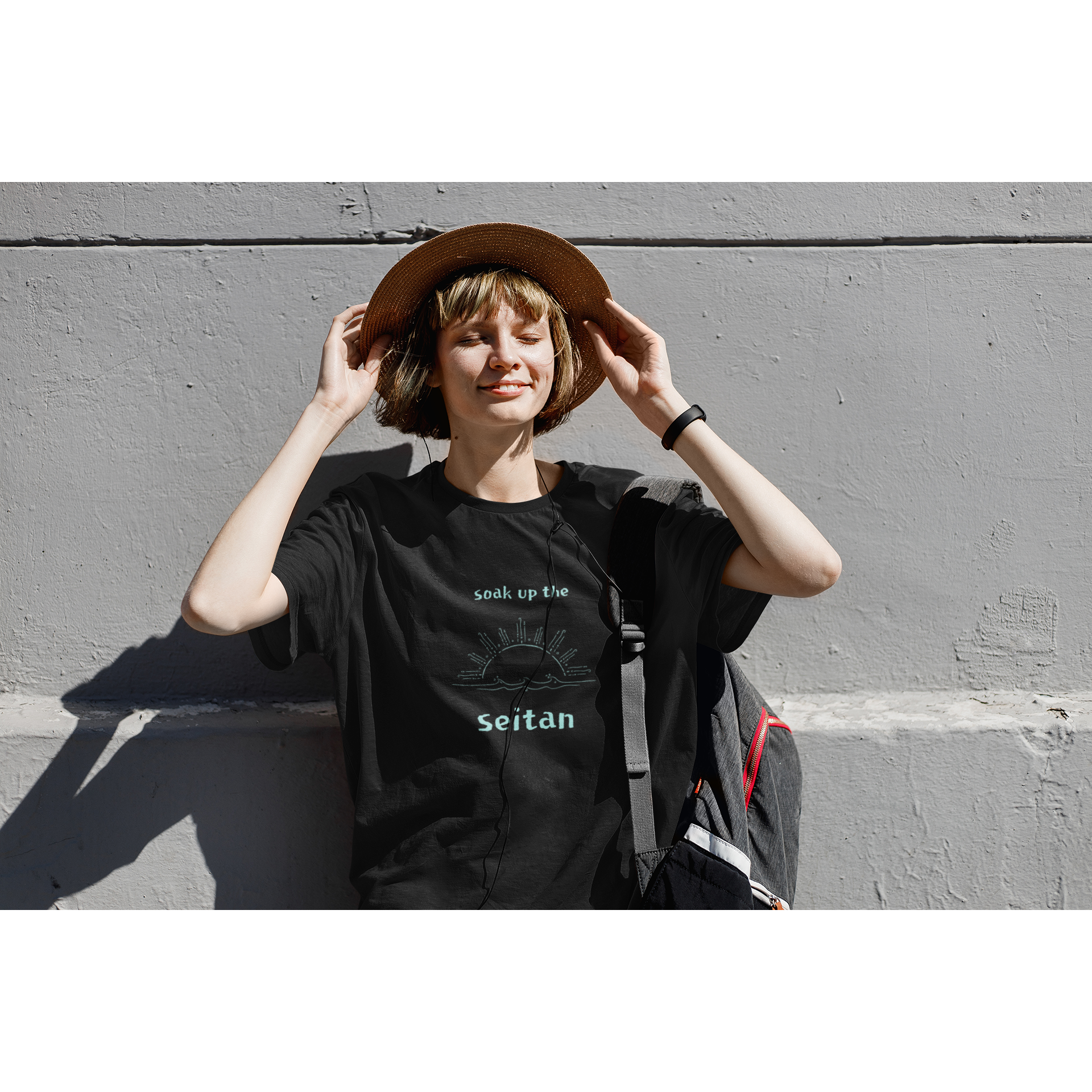 vegan t shirt in black with a teal design saying soak up the seitan worn by a woman smiling in the sun