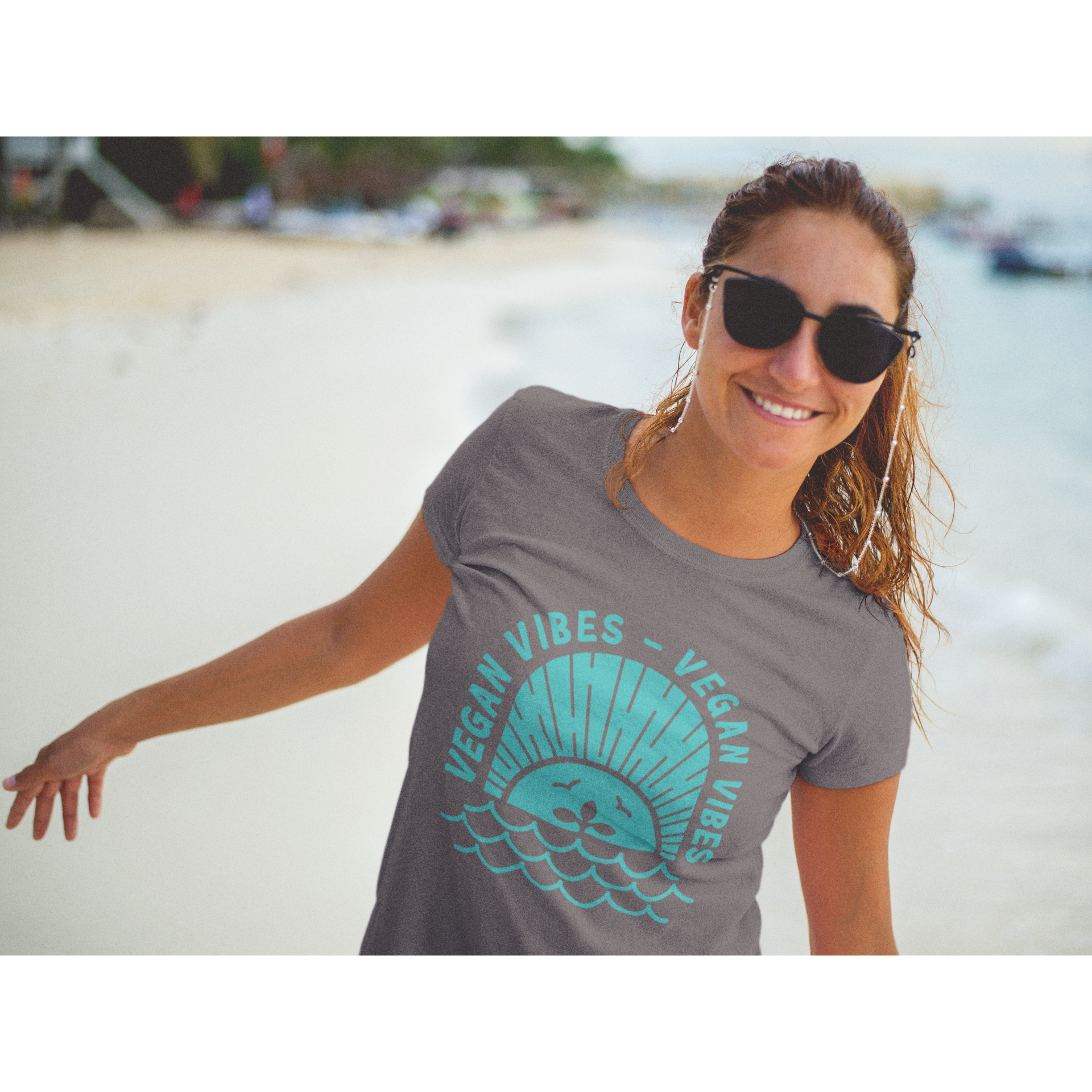 woman on a beach wearing a vegan t shirt with a teal vegan vibes design on asphalt colored premium cotton