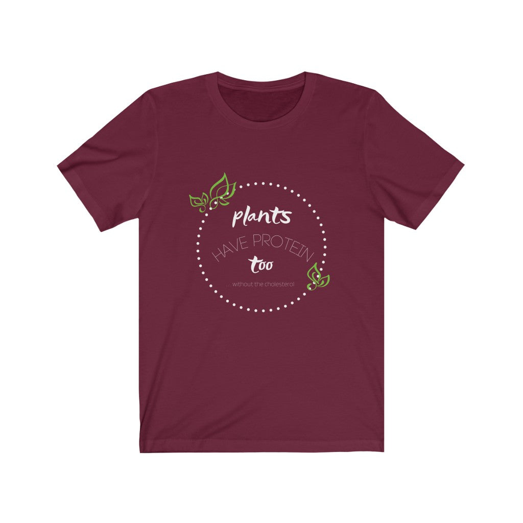 vegan clothing brands design on a maroon colored vegan t shirt, with design in white and green saying plants have protein too without the cholesterol, laying flat on white background, from ethical clothing brands and companies that donate to nonprofits