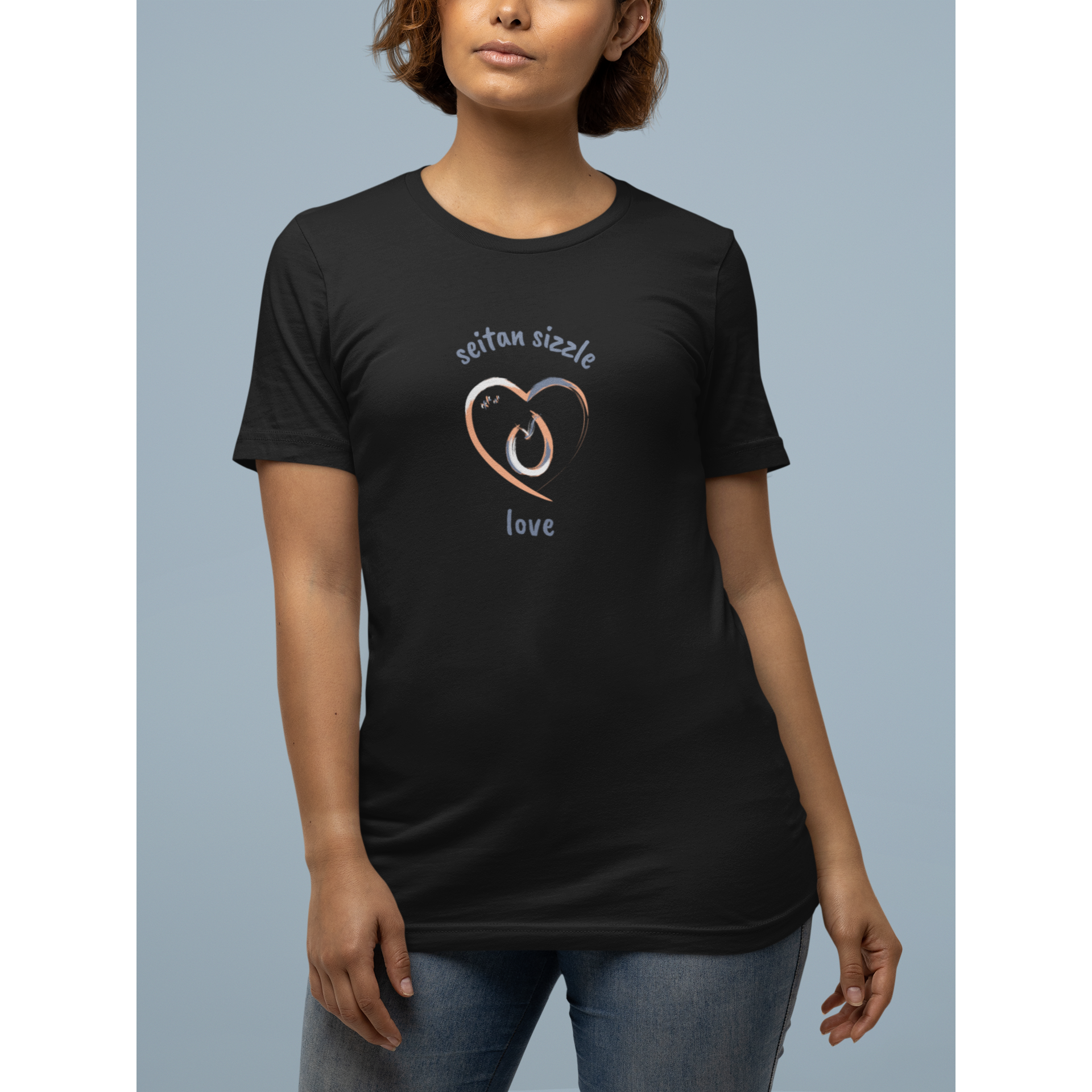 black vegan t shirt with a brushed design saying seitan sizzle love and a heart worn by a smiling woman