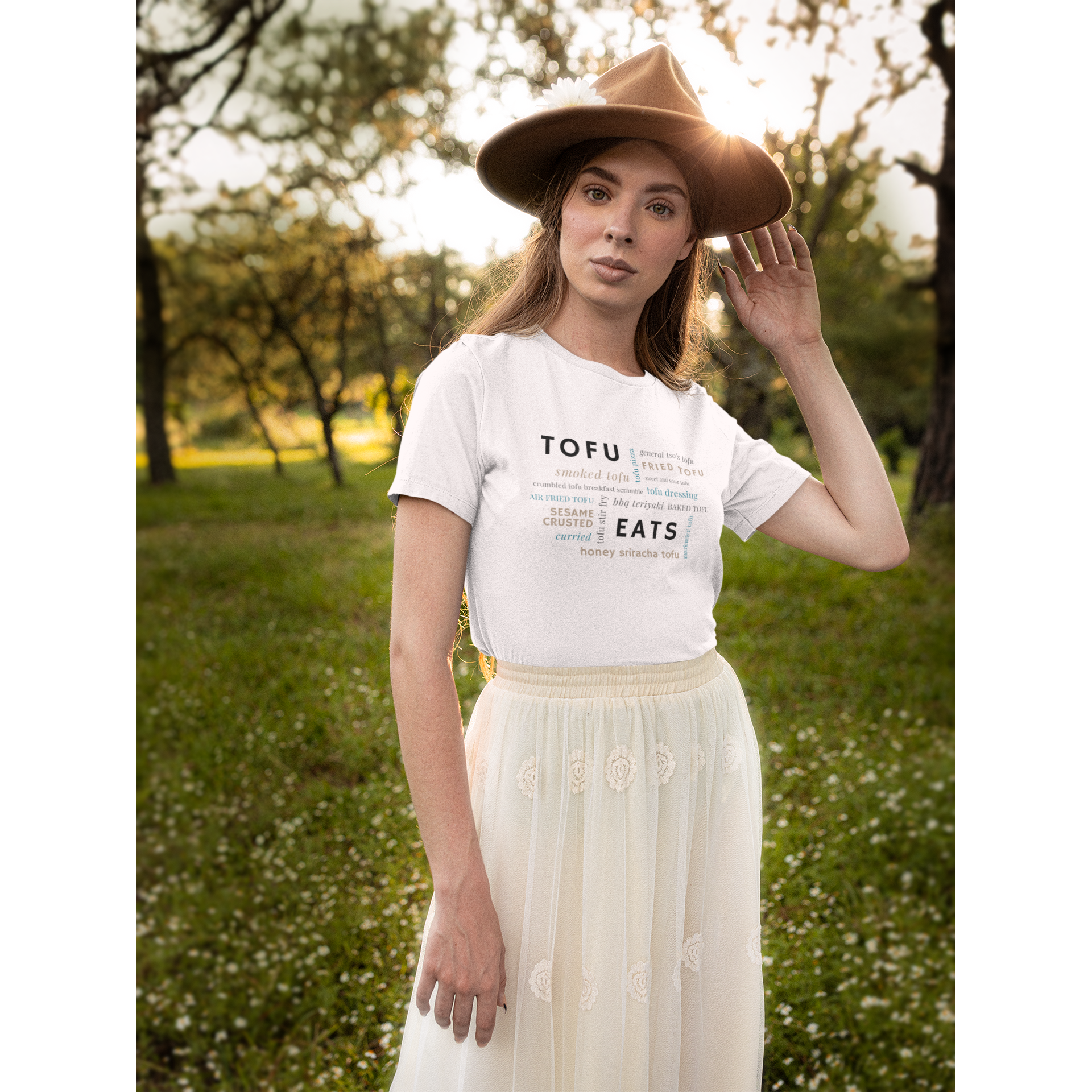 tofu shirt design with a tofu eats word salad design on a white premium vegan t shirt worn by a woman outside with a hat and skirt