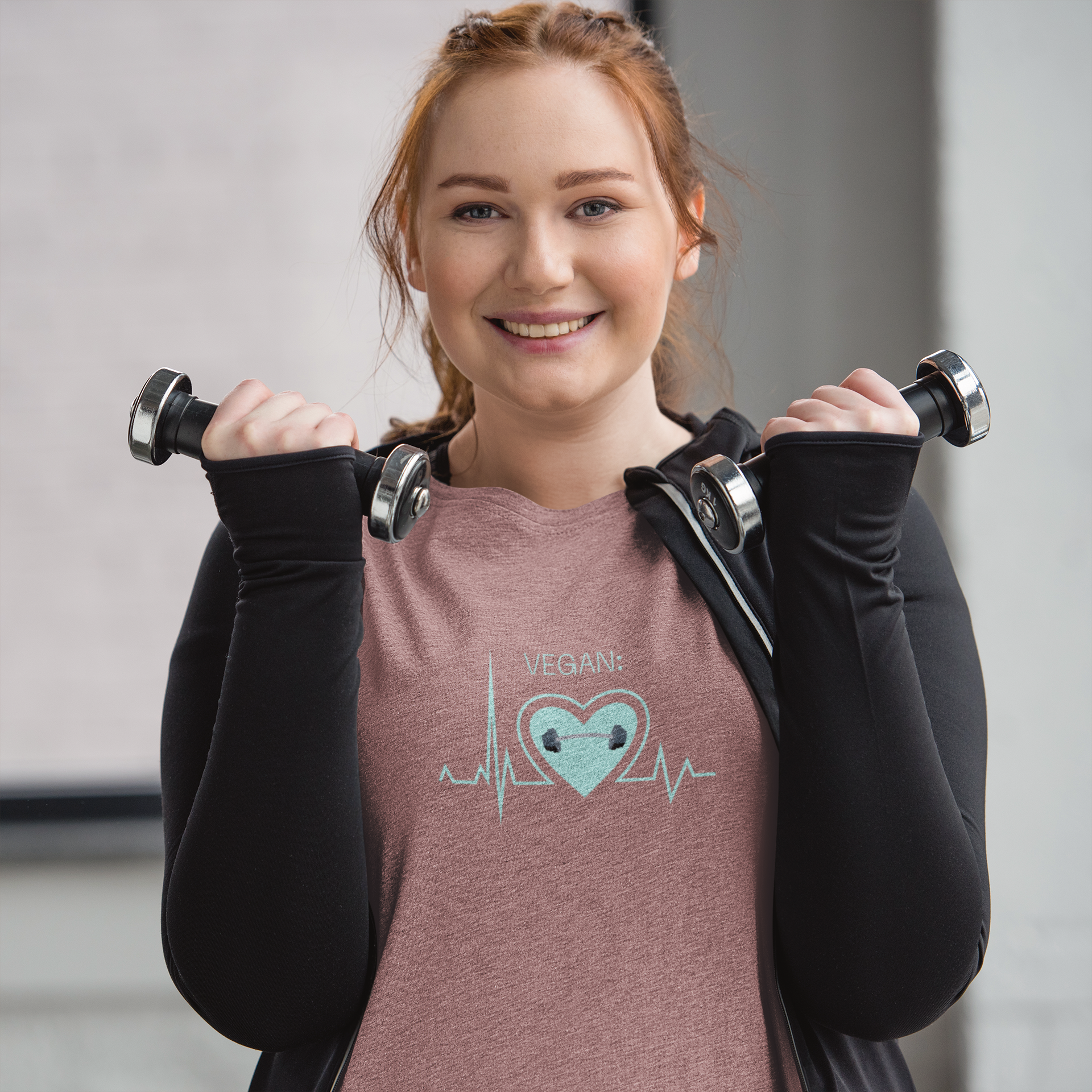 vegan heartbeat t-shirt with a dumbbell, in the color Heather Mauve worn by a woman at the gym